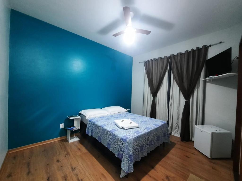 Dormitorio azul con cama y pared azul en Alvorada Guest House, en Caxambu