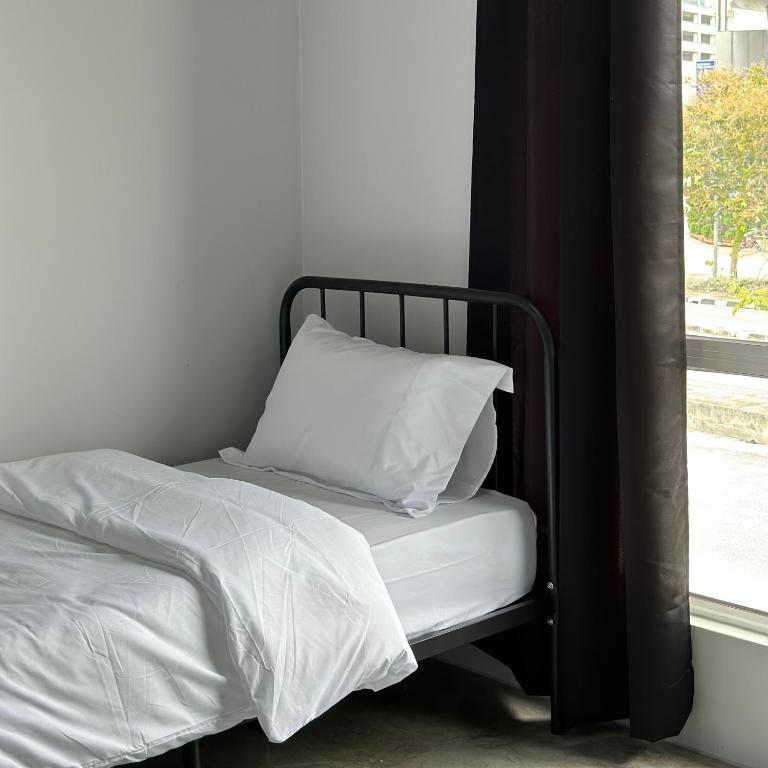 a bed with white sheets and a pillow next to a window at Be Right Back Homestay in Bukit Mertajam