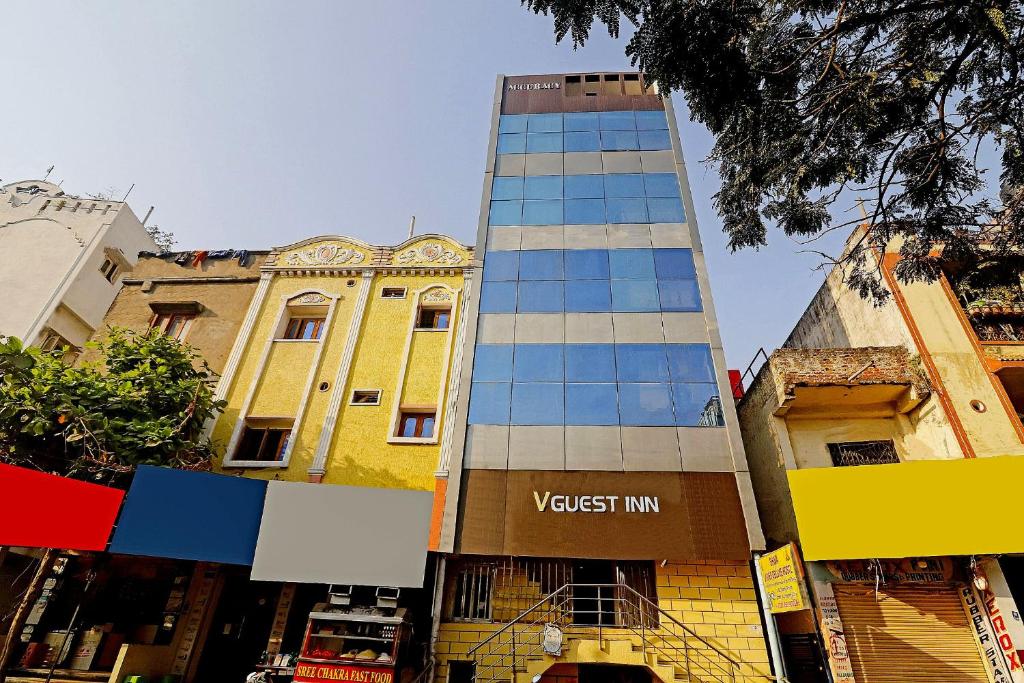a tall building in front of a yellow building at Guest Inn Near Hyderabad Central in Hyderabad