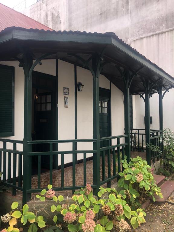 un edificio verde y blanco con porche en Villa Tamen - Colonia en Colonia del Sacramento