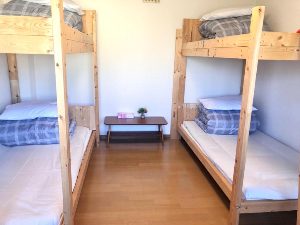 two bunk beds in a room with a table at Guest House Asahi in Otaru