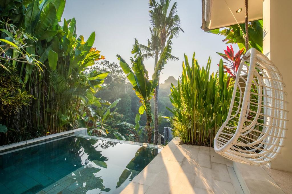 una piscina con sedia e vista sulla giungla di Villa Charles Ubud ad Ubud