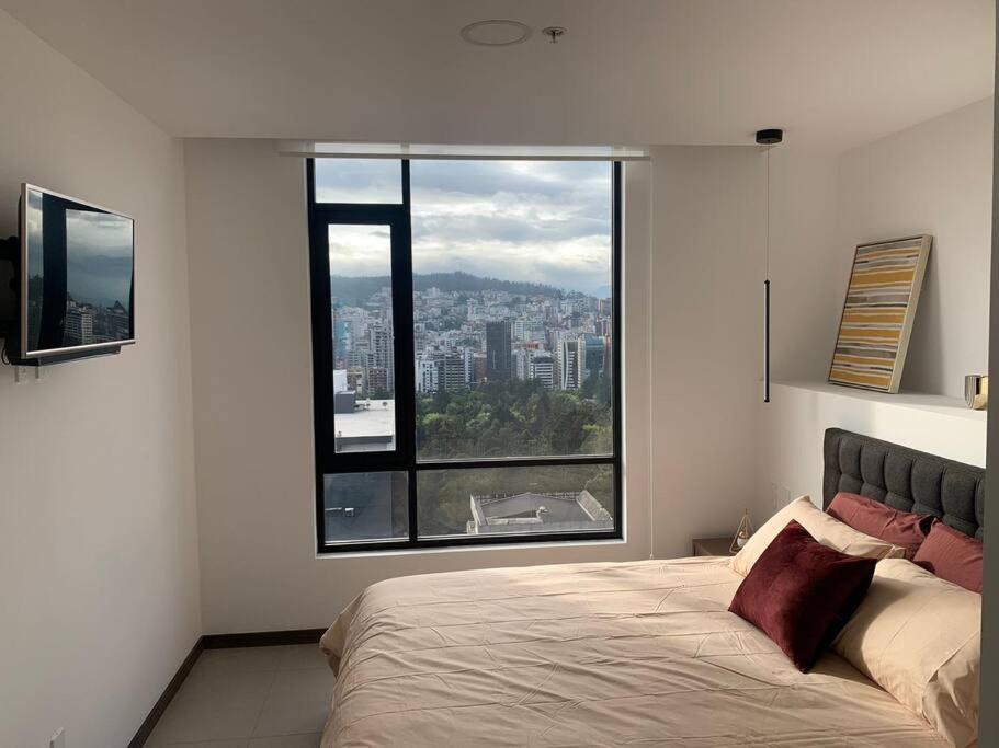 1 dormitorio con cama y ventana grande en Confort suite La Carolina, en Quito
