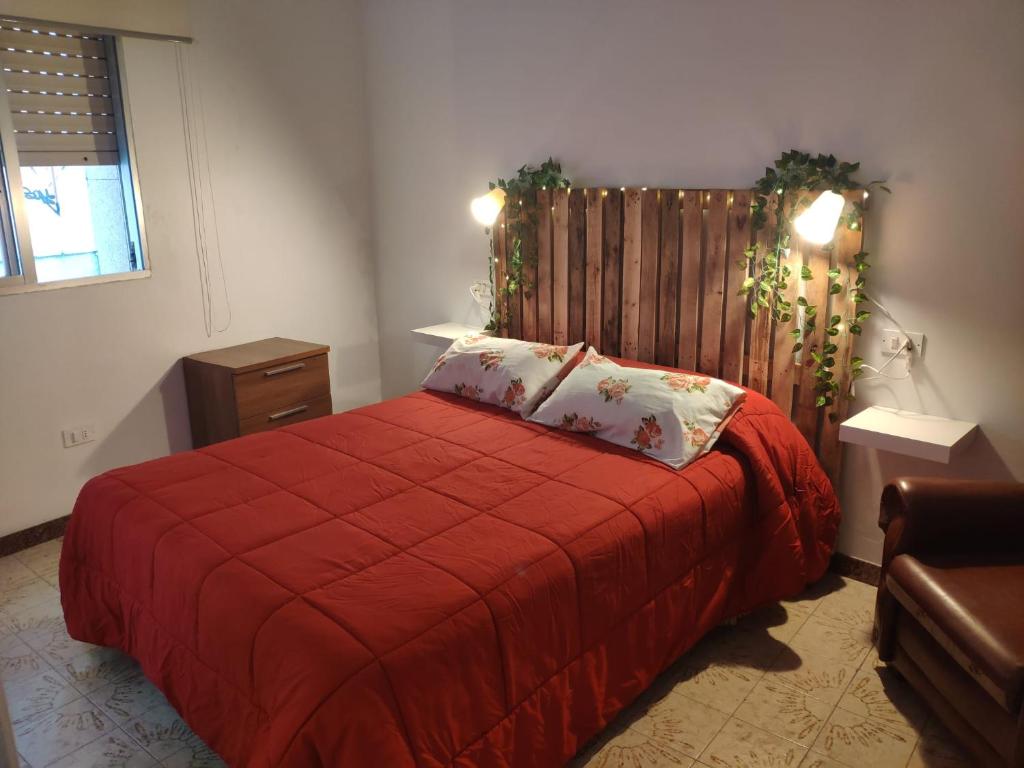 1 dormitorio con cama roja y cabecero de madera en Piso céntrico o grove, en O Grove