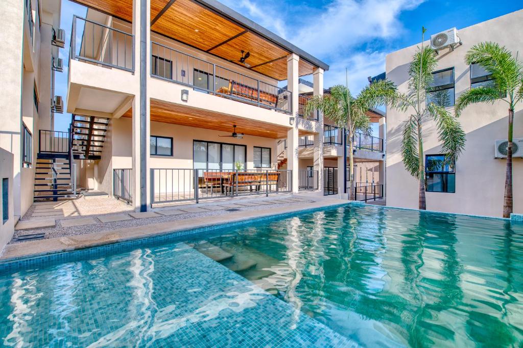 a swimming pool in front of a building with a house at Muna Tamarindo in Tamarindo