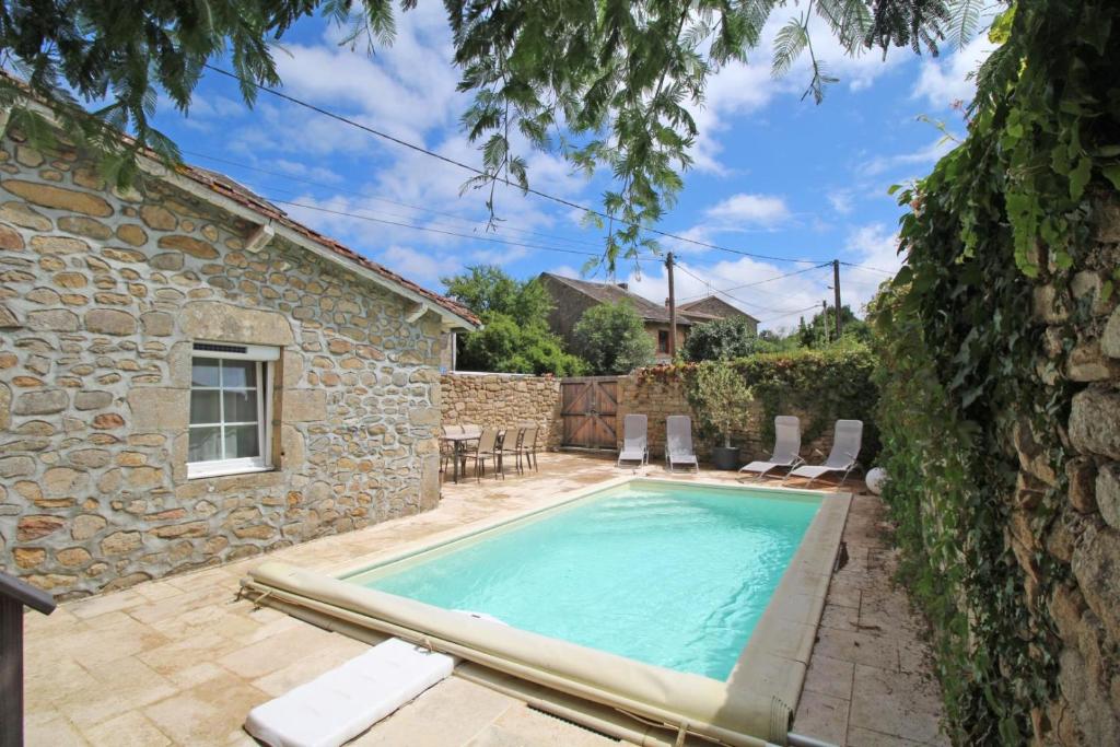 - une piscine en face d'une maison en pierre dans l'établissement Evasimone, à Châteauponsac