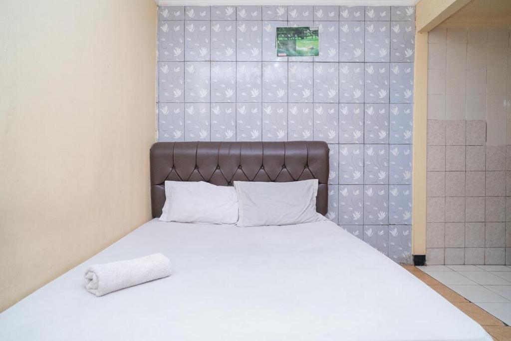 Schlafzimmer mit einem weißen Bett mit einem Kopfteil aus Leder in der Unterkunft Sabar Mansion 22 Mitra RedDoorz in Jakarta