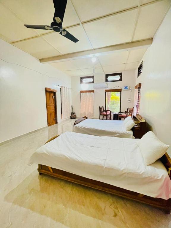 sypialnia z 2 łóżkami i wentylatorem sufitowym w obiekcie Namdang Homestay w mieście Sibsāgar