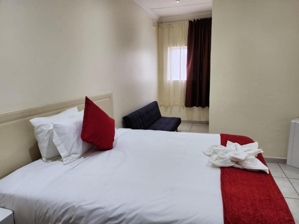 1 dormitorio con 1 cama blanca grande con almohadas rojas en Oslo Beach Home Feeling, en Port Shepstone