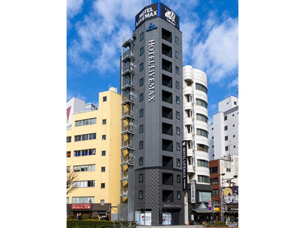 Un grand bâtiment avec un panneau en haut dans l'établissement HOTEL LiVEMAX Asakusabashi-Ekimae, à Tokyo