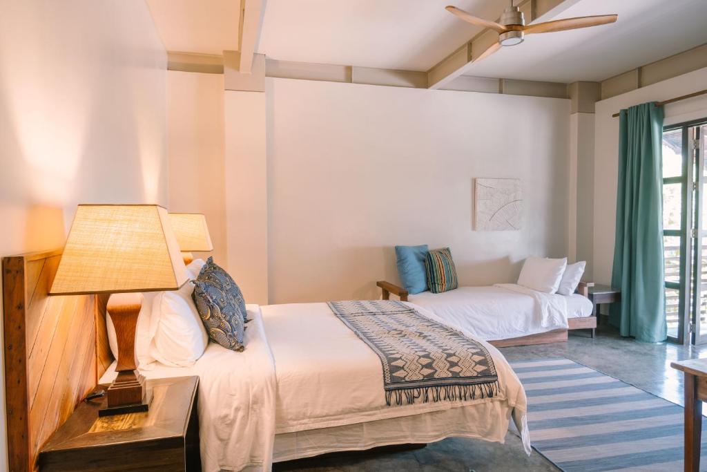 a hotel room with two beds and a lamp at Kaimana Resort Siargao in General Luna