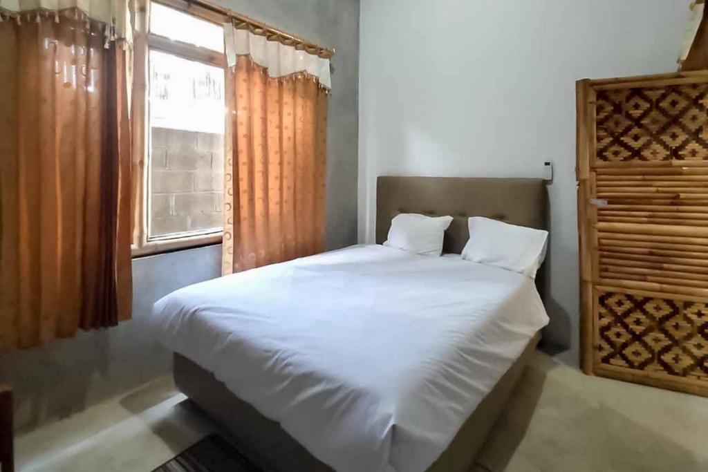 ein Schlafzimmer mit einem weißen Bett und einem Fenster in der Unterkunft Sukawana Guest House Mitra RedDoorz 