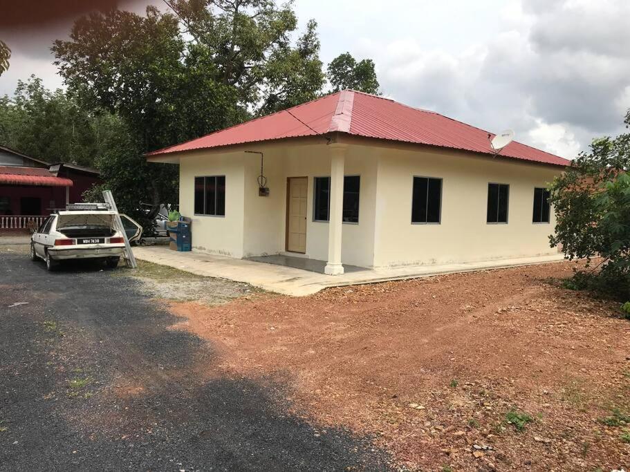 une petite maison blanche avec un toit rouge dans l'établissement Hajjah Homestay Asun, Jitra, Alor Setar Kedah, à Jitra