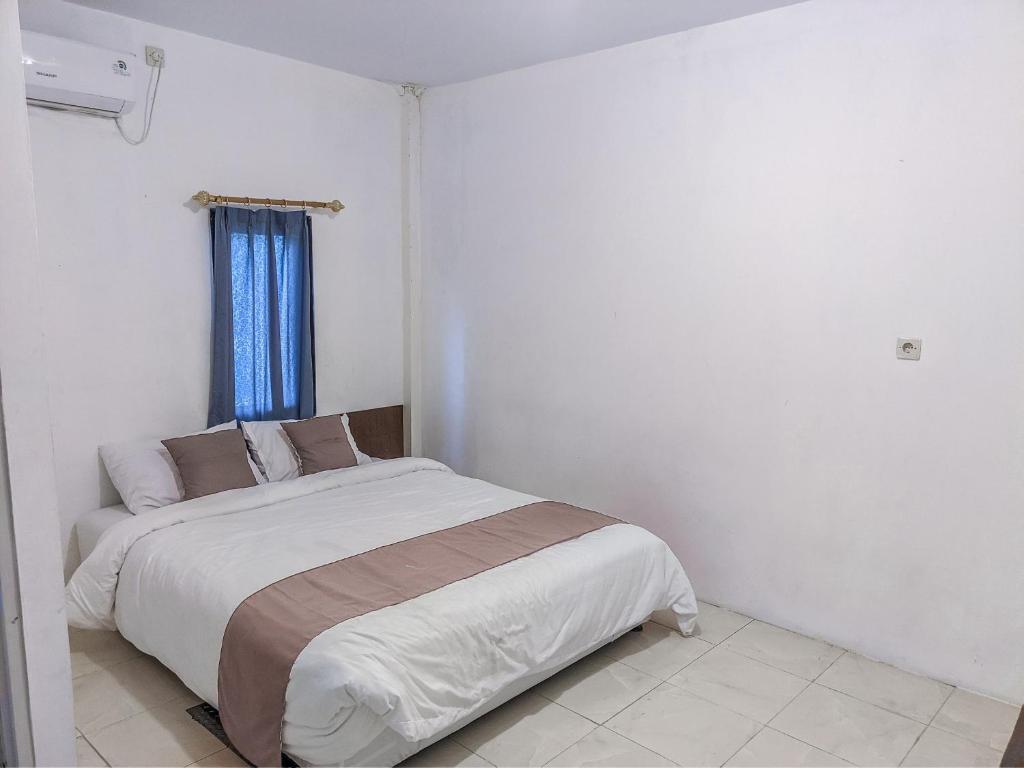 a white bedroom with a bed with a blue window at Rumah Ceria near Bandara Ahmad Yani Semarang RedPartner in Kalibanteng-lor