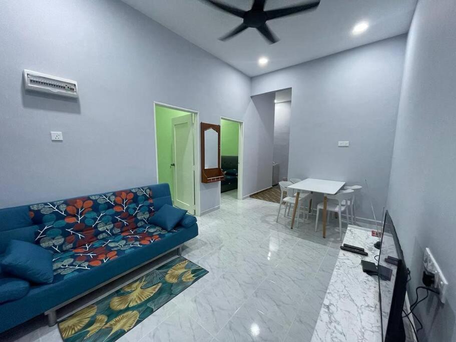 uma sala de estar com um sofá azul e uma mesa em Homestay 4S em Marang