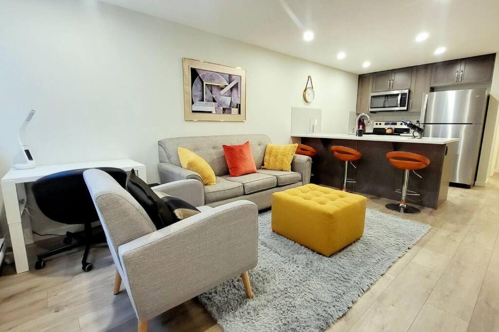 een woonkamer met een bank en een gele kruk bij The Oliver - Cozy Apartment in Rockland Park, NW in Calgary