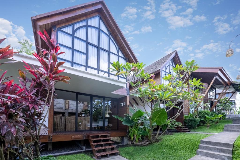 a house with a lot of windows and plants at Villa Atra Bambulogy by Nagisa Bali in Kerobokan