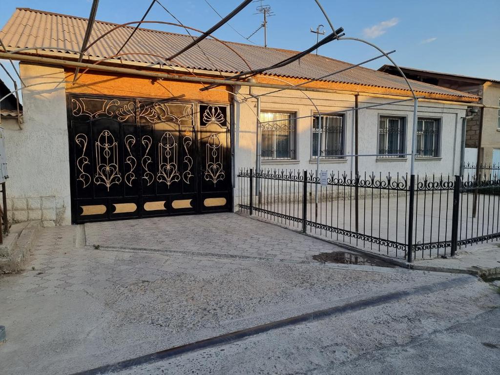 um portão preto em frente a uma casa branca em Deluxe em Shymkent