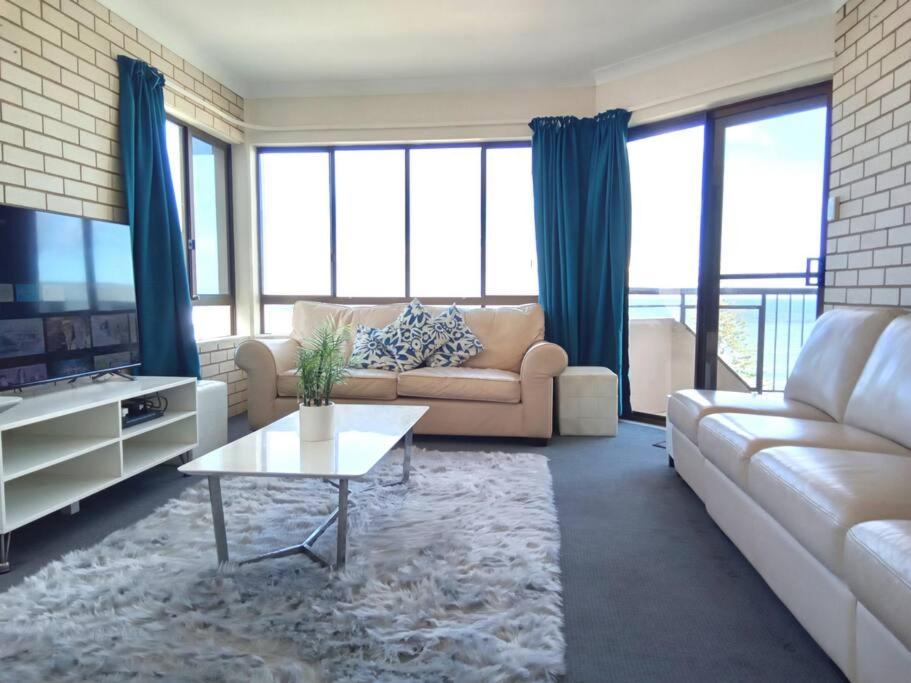 a living room with a couch and a tv at Ocean view beachside 3 bedroom 2 bathroom unit in Caloundra