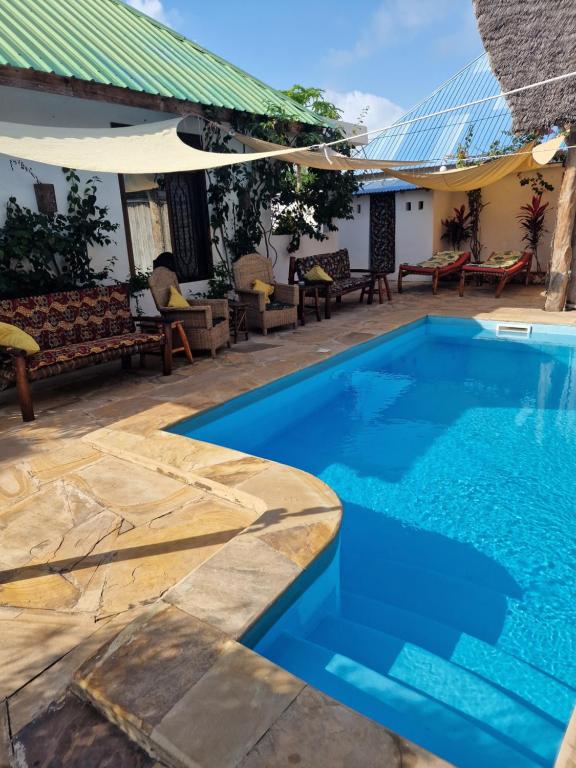 a swimming pool in front of a house with a patio at Villa Kirumi in Nungwi