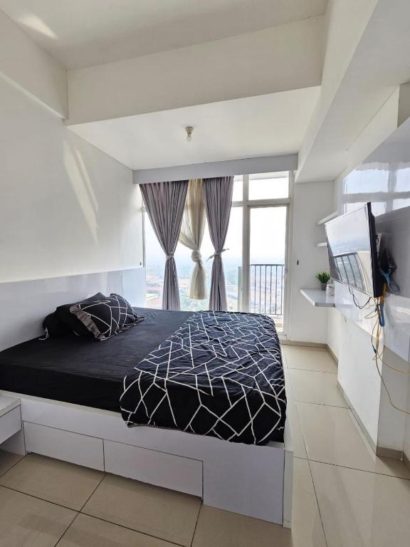 a bedroom with a bed and a large window at RoomQu at Apartment Tree Park in Kebonnanas