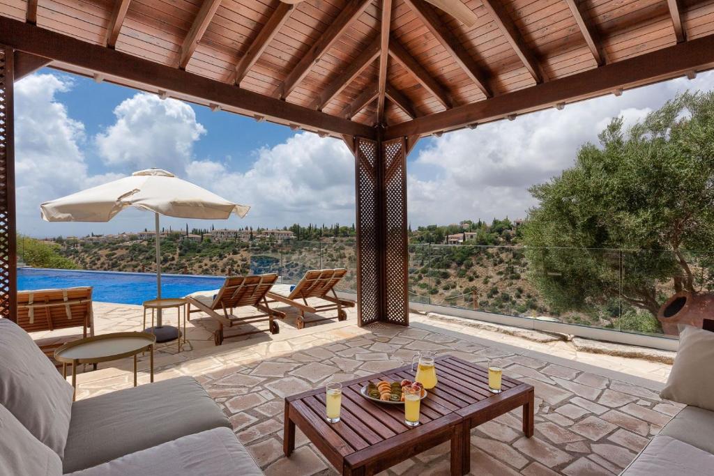 un patio con tavolo, sedie e piscina di Aphrodite Hills 4 bedroom villa with private infinity pool a Kouklia