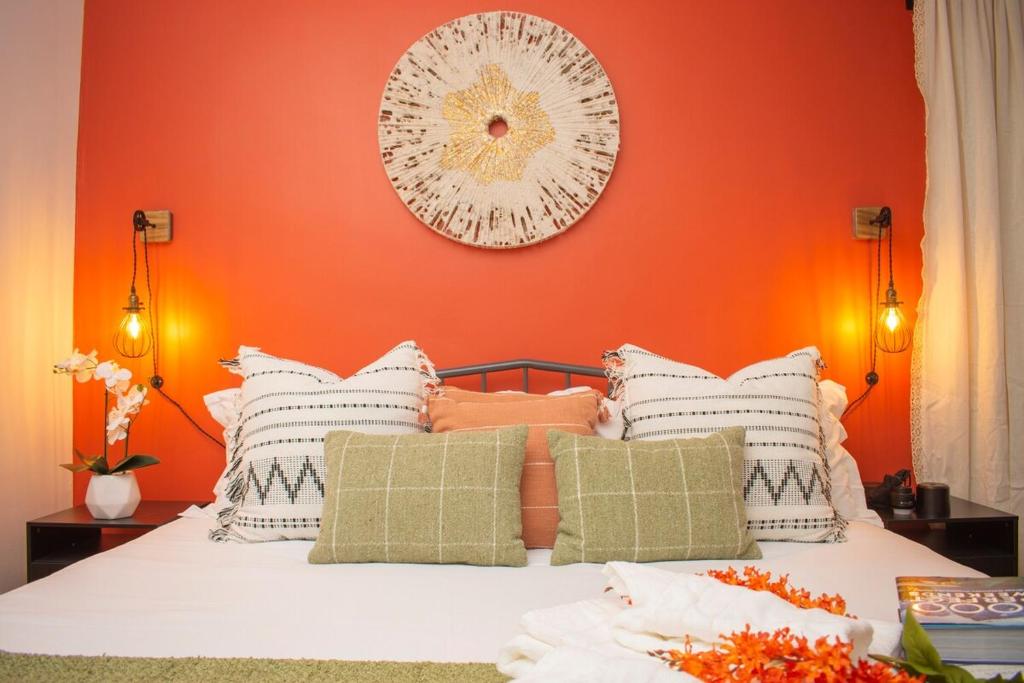 1 dormitorio con pared de color naranja y 1 cama con almohadas en Derbyshire Rustic Bohemian, en Cleveland Heights