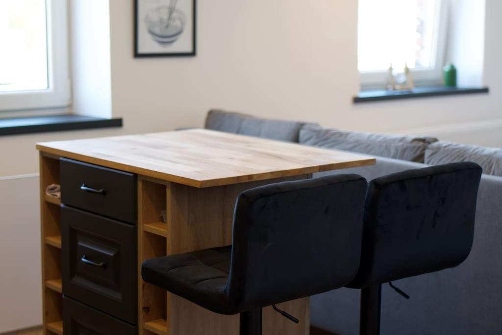a wooden table with two black chairs and a desk at Modern apartment close to Katowice Center! in Katowice