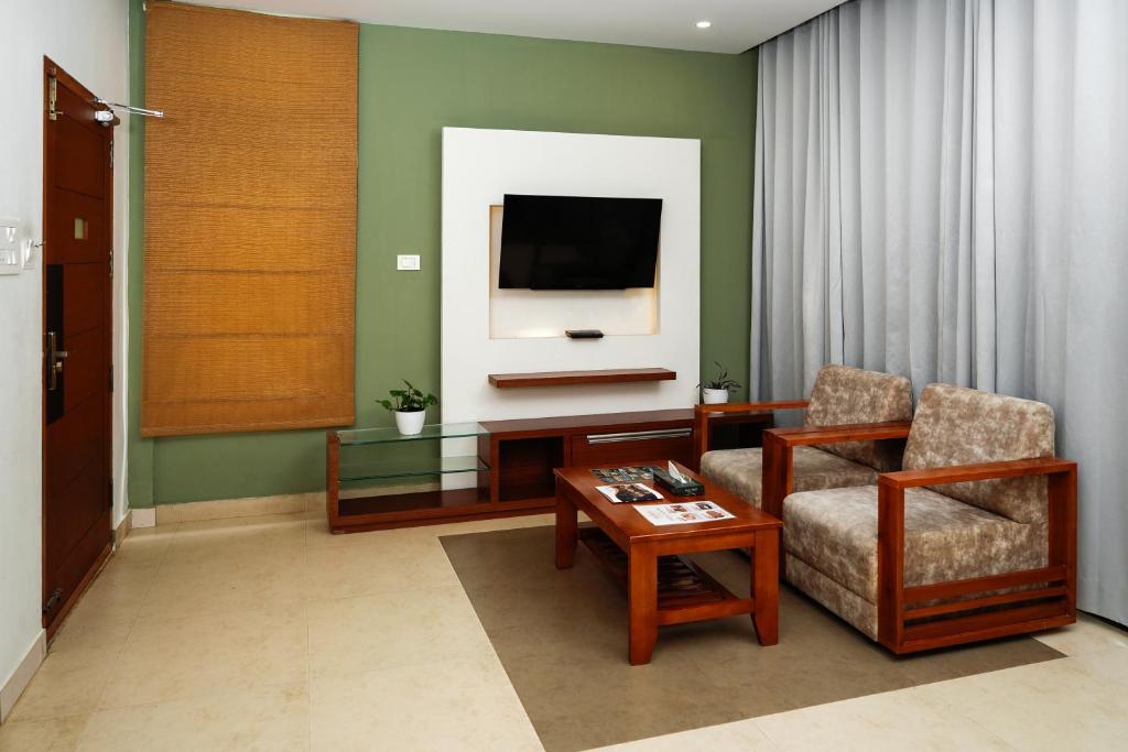 a living room with a tv and a chair and a table at Kuruva Island Resort And Spa - By KABINI BREEZE, Wayanad in Mananthavady