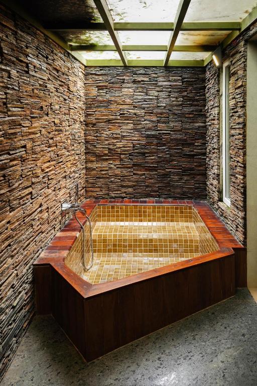 a room with a bath tub in a brick wall at Kuruva Island Resort And Spa - By KABINI BREEZE, Wayanad in Mananthavady
