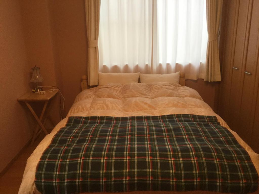 a bed with a plaid blanket and a window at Cheese Cozy Condo in Tokyo