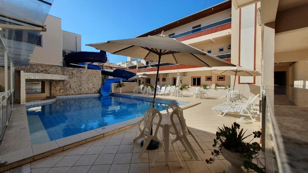 佛羅安那波里的住宿－Tropicanas Hotel e Eventos，一个带椅子和遮阳伞的游泳池以及滑梯