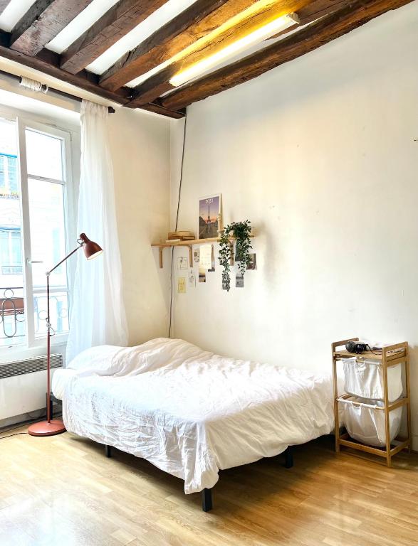 a bedroom with a bed and a lamp and a window at [New] Cozy studio Center of PARIS / Bourse in Paris