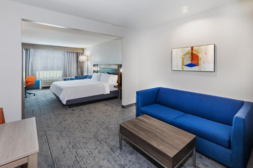 a hotel room with a bed and a blue couch at Holiday Inn Express Houston Space Center-Clear Lake, an IHG Hotel in Webster