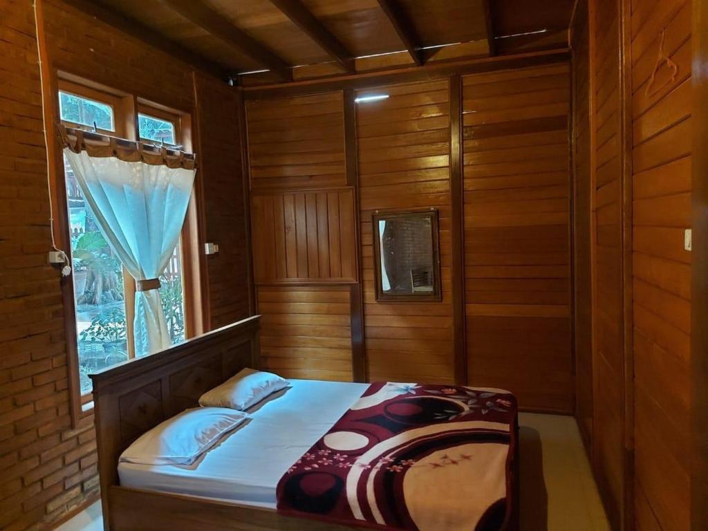 een slaapkamer met een bed in een kamer met een raam bij Roemah Kayu Saragan Syariah Magelang Mitra RedDoorz 