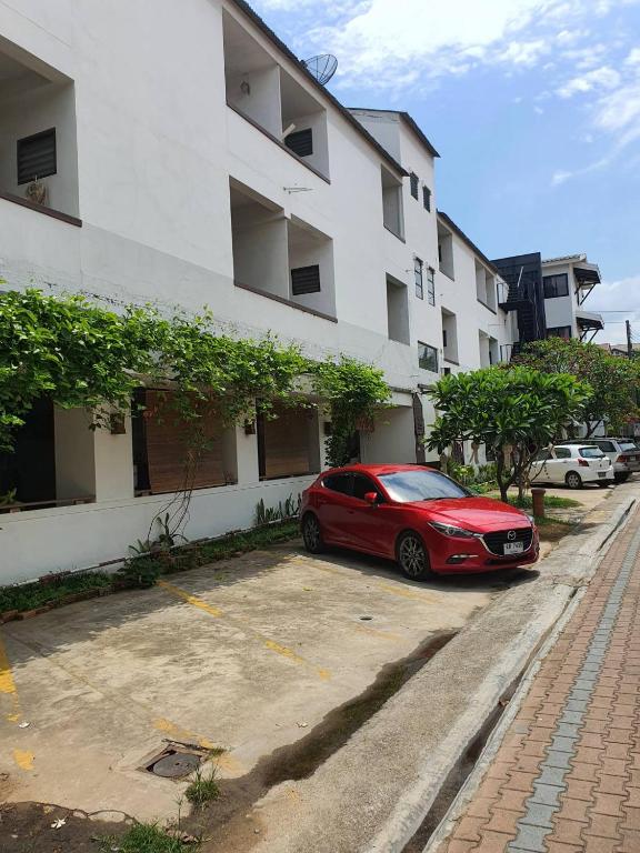 a red car parked in a parking lot in front of a building at Mali's Room in Chiang Mai