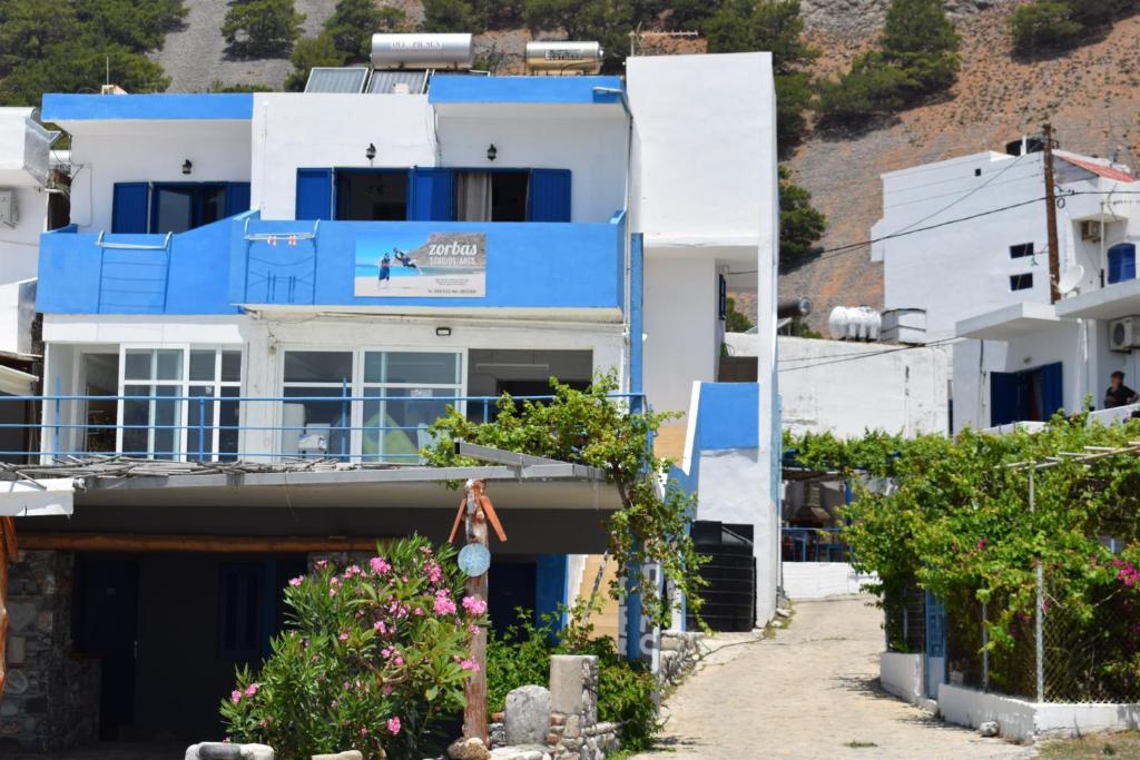 a blue and white building with a balcony at Zorbas Studios in Agia Roumeli