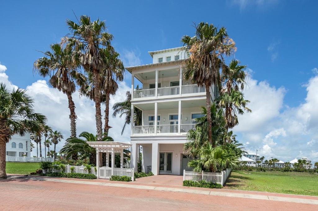 una casa blanca con palmeras delante en Lotus Villa - Private beach house with Pool and Hot Tub home, en South Padre Island