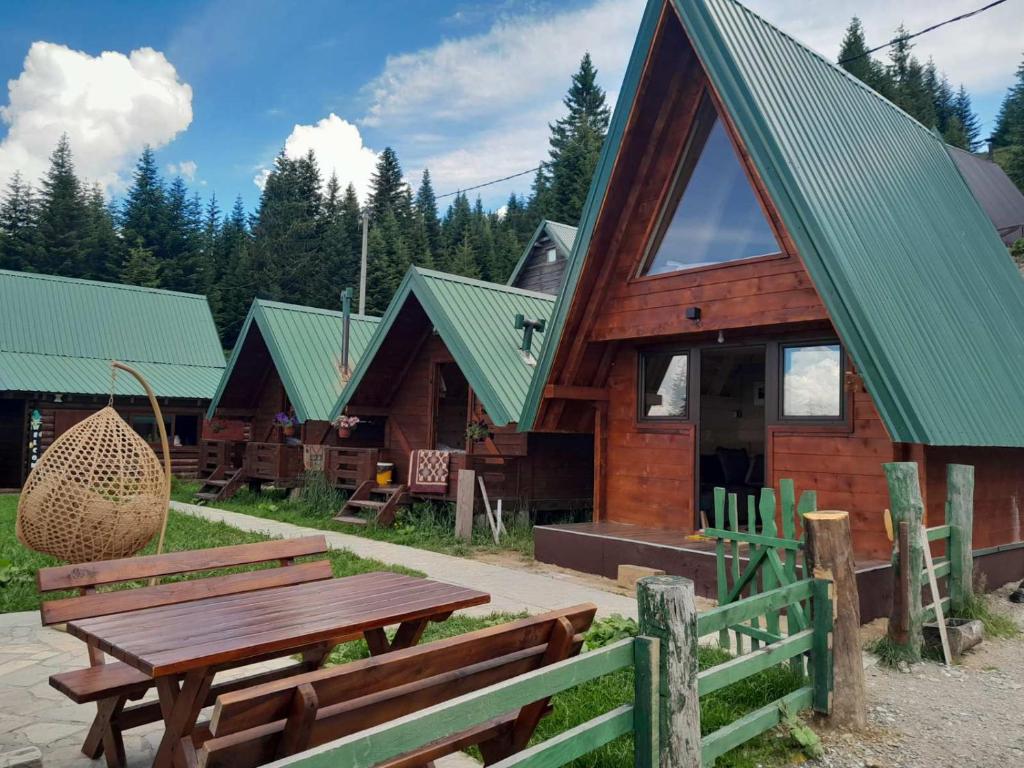 a wooden cabin with a picnic table and benches at Komovi - Kobil Do Guesthouse in Kolašin