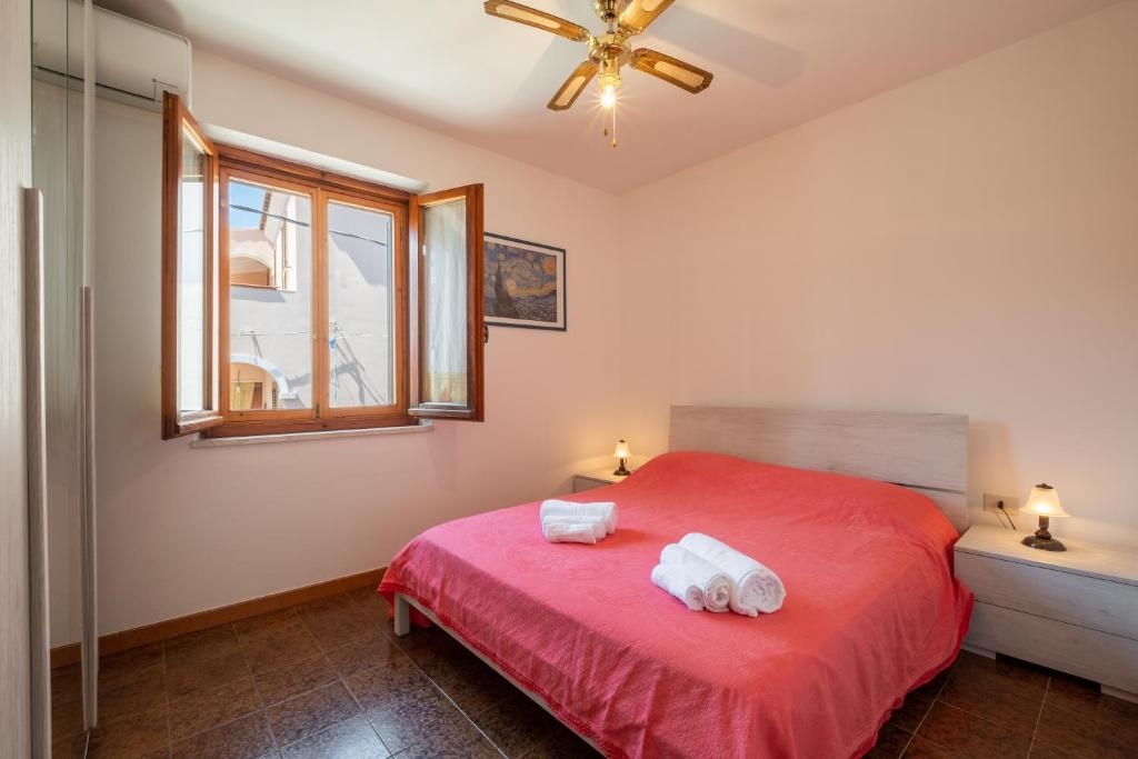 een slaapkamer met een rood bed en 2 handdoeken erop bij [5 Min Budoni]Terrazzo Vista Borgo & Self Check-In in Tanaunella