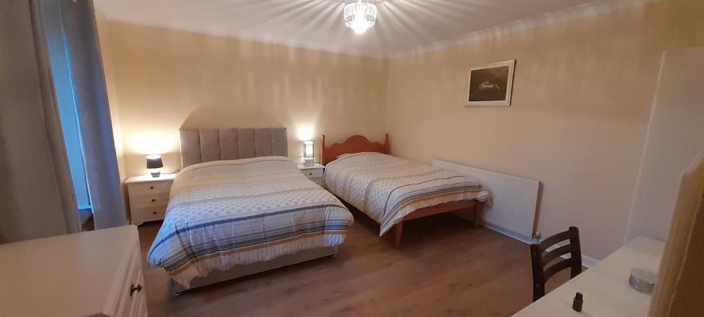a bedroom with two beds and a table with two lamps at Biddys cottage in Donegal