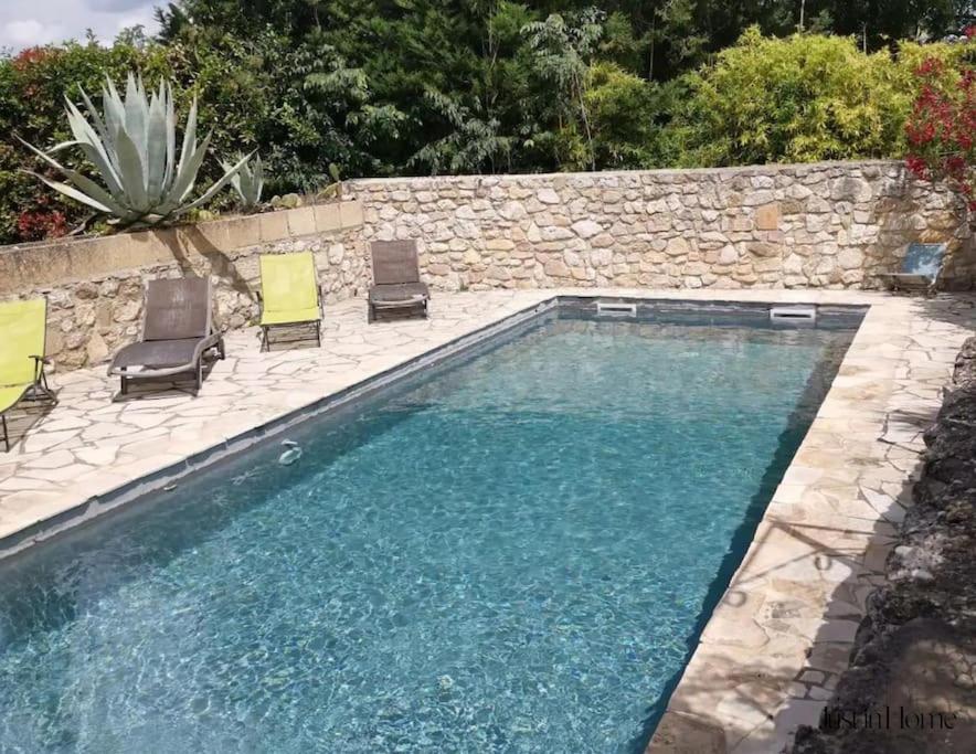 a swimming pool with chairs and a stone wall at Mas en pierre de 300m2, piscine, terrasse, 4 chbre in Sainte Anastasie - Aubarne