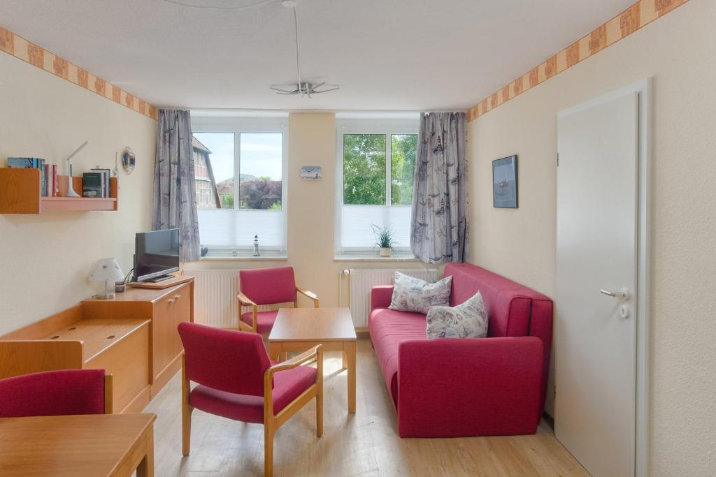 uma sala de estar com um sofá vermelho e cadeiras em Apartment 8 em Heiligenhafen