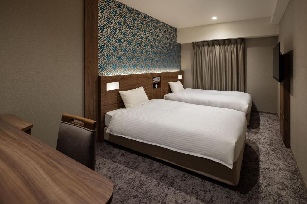 a hotel room with two beds and a tv at the b namba-kuromon in Osaka