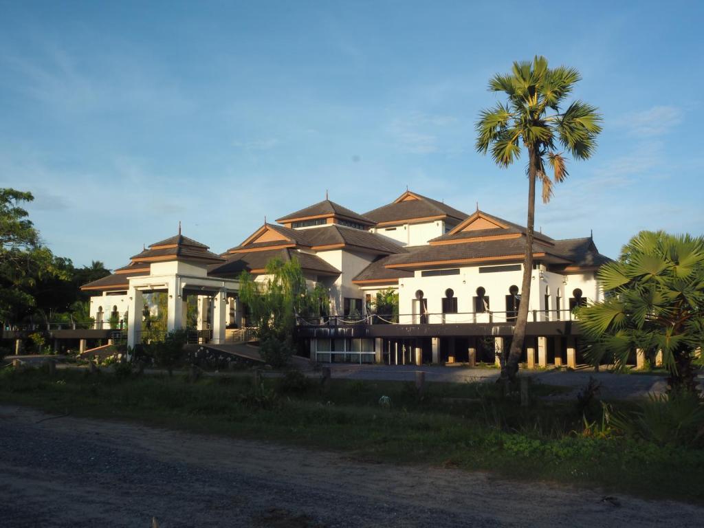 a large building with a palm tree in front of it at Bakkahland Farm and Resort in Pattani