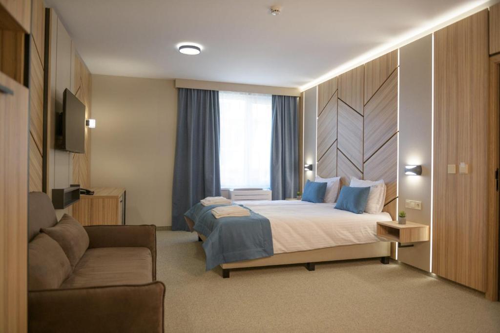 a hotel room with a bed and a couch at Hotel Forum City in Pazardzhik
