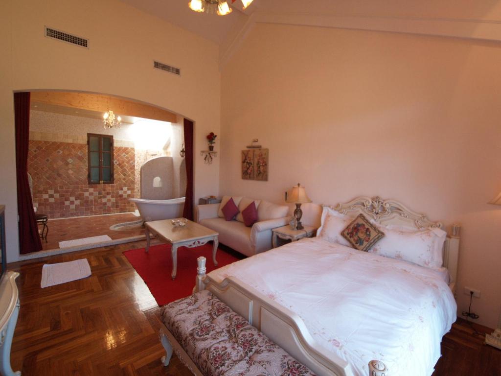 a bedroom with a white bed and a couch at Kenting Tuscany Resort in Kenting