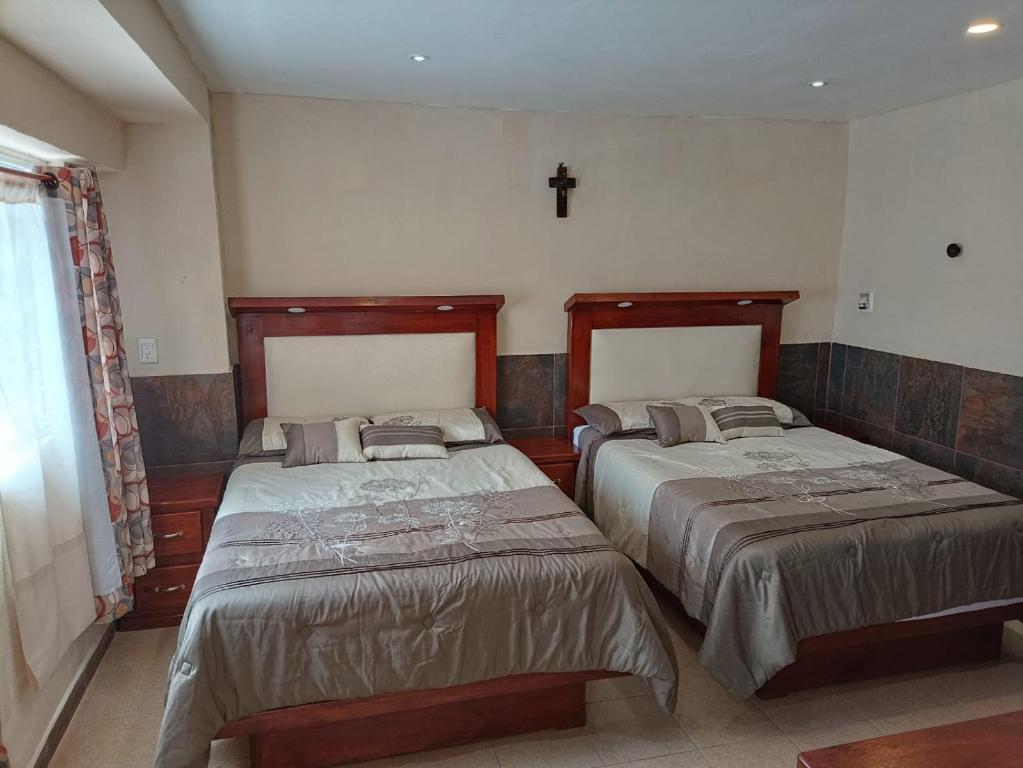 a bedroom with two beds and a cross on the wall at Departamento Aeropuerto CDMX in Mexico City