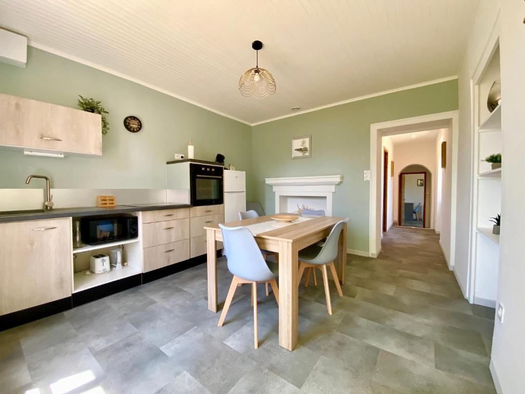 eine Küche mit einem Holztisch und Stühlen in der Unterkunft Maison Calme avec extérieur 
