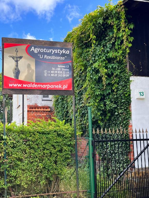 una señal frente a un edificio cubierto de hiedra en Agroturystyka „U Rzeźbiarza”, en Sławno